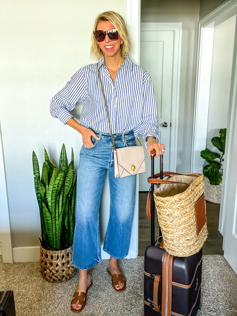 Travel outfit for  spring/summer Sarah is wearing wide leg jeans, stripe shirt, sandals, crossbody bag